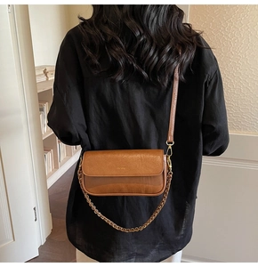 Detailed back view of a model wearing a caramel brown leather baguette bag with chain strap