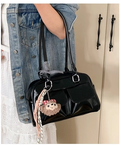 Detail of glossy black Boston bag with decorative ribbons and plush bear charms