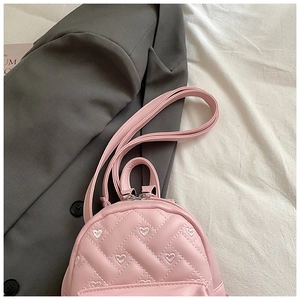 Detailed macro view of pink PU leather backpack with heart embroidery and diamond quilting