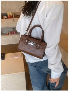 Detailed side view of a dark brown pleated leather handbag worn as a stylish crossbody bag