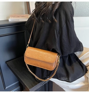Detailed view of a brown vintage baguette bag with gold chain strap on a model