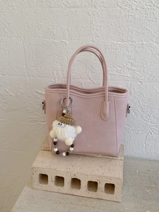 Sac seau en cuir rose pâle avec pendentif monstre en peluche sur socle en pierre