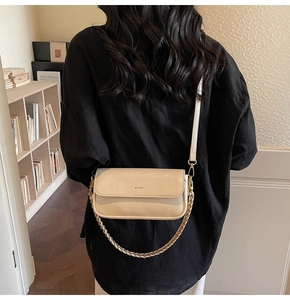 Detail showing the 'NO FILTER' lettering on a beige minimalist crossbody bag with chain strap