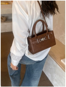 Detail of a brown vintage tote bag with heart-shaped silver metal buckle and PU leather texture