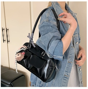 Detail of black PU shoulder bag with cargo pockets, checkered bow and plush charm accessory