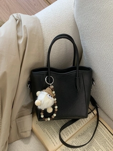 Sac seau minimaliste en cuir noir avec pendentif peluche et bandoulière réglable