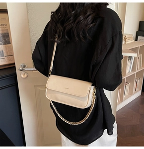 Detail of minimalist beige baguette bag with gold chain and NO FILTER lettering