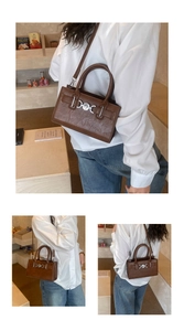 Detailed close-up of dark brown handbag showing leather texture and silver buckle