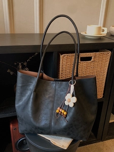 Sac cabas noir en cuir texturé avec pendentif fleur dans un décor de style vintage