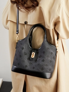 Vintage textured leather bucket bag with gold hardware worn over a beige trench coat