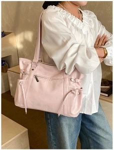 Detail of a pink leather tote bag featuring a front zipper pocket and side drawstring accents