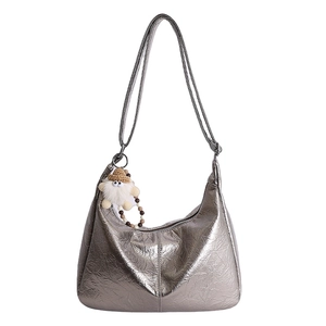 Silver metallic tote bag with pleated texture and plush charm on white background