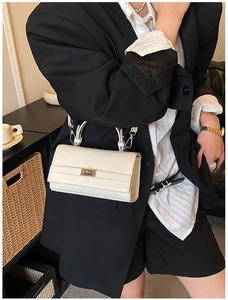 Detail of white crocodile pattern handbag with silver clasp on a stylish model