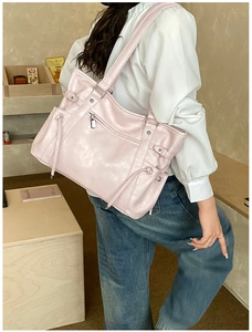 Close-up of light pink large capacity tote bag worn on shoulder in a warm indoor setting