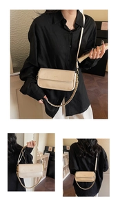 Detail of cream baguette bag with NO FILTER lettering and woven metal chain strap