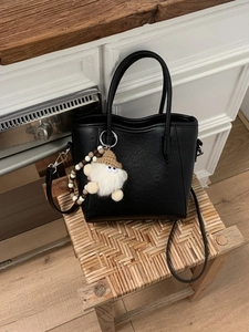 Sac seau minimaliste en cuir noir avec poignées et accessoire de poupée en peluche