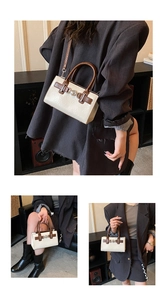 Detail of vintage beige crossbody bag with brown leather handles and metal clasp