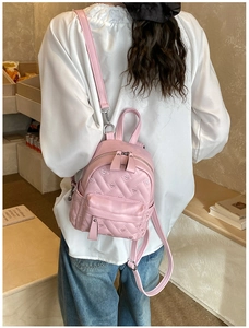 Detail of pink quilted backpack with heart patterns and zipper worn on shoulder