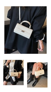 Detail of cream crocodile textured handbag featuring silver twist lock and round top handle