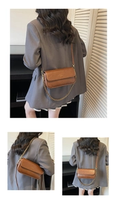 Detail of caramel leather baguette bag with a gold chain strap and slim shoulder strap