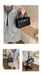 Detail of a black faux leather boston handbag with silver metal ring and double handles