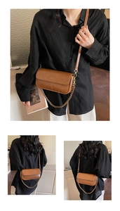 Detail of vintage brown leather baguette bag with gold chain strap and No Filter slogan