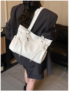 Detailed view of a white PU leather tote bag with drawstrings on a charcoal suit model