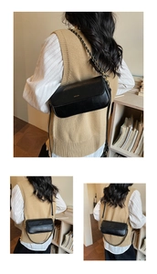 Macro detail of black leather baguette bag featuring gold NO FILTER lettering and chain strap