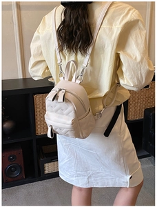 Detail of a cream mini backpack with quilted heart pattern and adjustable straps
