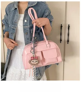 Detailed view of pink glossy PU leather Boston bag featuring dual front pockets and cute monkey charm