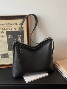 Minimalist black PU leather tote bag with shoulder strap and tag in a vintage office setting