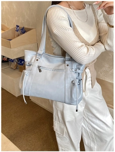 Detail of light blue large leather tote bag with functional zipper and side drawstrings