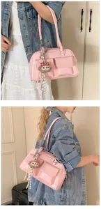 Detail view of pink glossy Boston bag featuring front pockets and plush monkey keychain