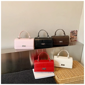 Close-up of five mini crocodile pattern handbags with silver metallic turn locks in various colors
