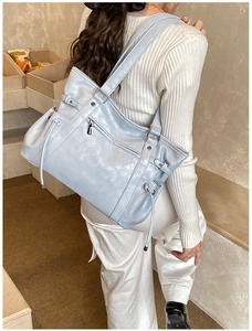 Detail of light blue tote bag with drawstring side pockets and sleek silver zipper accents