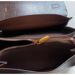 Détail intérieur du sac en cuir marron avec fermeture éclair dorée et compartiments