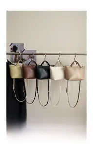Row of five elegant crossbody bags in beige caramel black and ivory on a metal rack