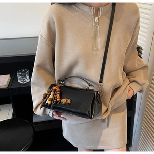 Détail du sac à main noir avec fermoir doré et pampille décorative en perles de bois