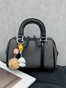 Sac Boston gris texturé avec finitions en cuir noir et breloques décoratives de vue latérale