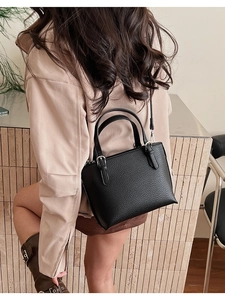 Close-up of black lychee grain leather handbag featuring silver hardware and a strap