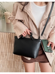 Detail of minimalist black leather crossbody bag with silver hardware and detachable strap