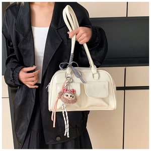 Detail of cream white faux leather tote bag with square pockets and ribbon handle bow