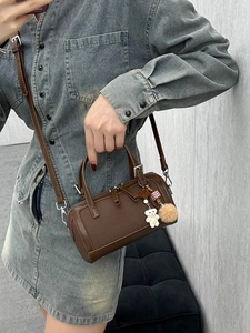 Dark brown pebbled Boston handbag with bear charm, showing crossbody and top handle style