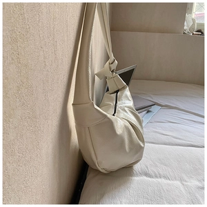 Detailed macro view of the creamy white hobo bag with knotted strap and lychee texture