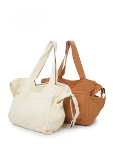 Detailed view of two large canvas tote bags with front pockets and adjustable straps