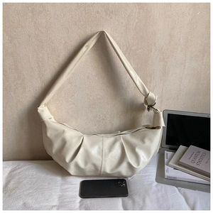Detail of cream pleated hobo bag with knotted strap on a minimalist lifestyle setting