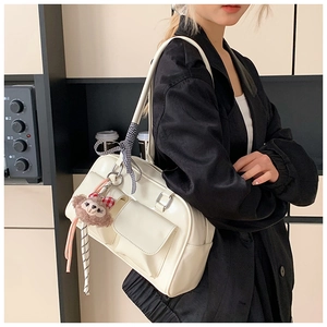 Model wearing a cream Boston shoulder bag with checkered bow and plush charm detail