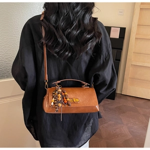 Détail d'un sac à main vintage en cuir marron avec gland en bois et fermoir rotatif