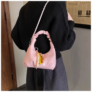 Pink glossy patent leather crescent bag shown on model with bead charm detail