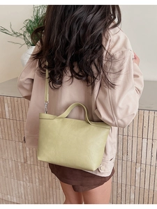 Model wearing a light green crossbody half-moon bag with silver metal hardware detail